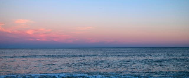 Pastel pink and blue twilight over the Atlantic Ocean with gentle waves on a quiet beach