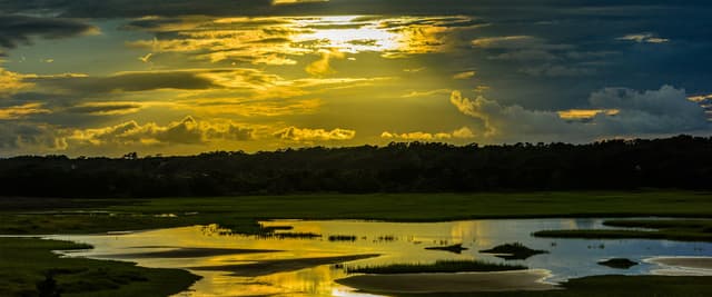 Holden Beach NC marshland at golden sunset with vivid storm clouds reflected in still water